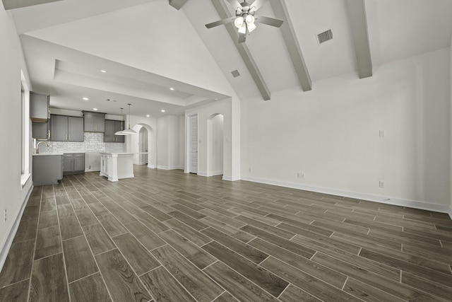 16738 Yaklin Meadow Ct, Humble, TX 77346 - unfurnished living room with arched walkways, beamed ceiling, dark wood-type flooring, recessed lighting, and a ceiling fan