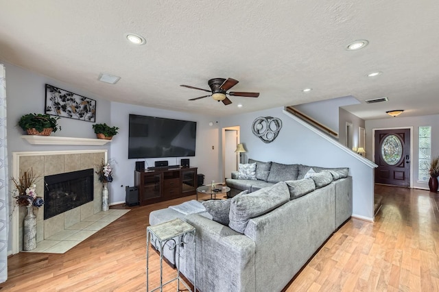 16307 Mango Ridge Ct, Humble, TX 77396 - living room featuring ceiling fan, a textured ceiling, light wood-style floors, recessed lighting, and a tile fireplace