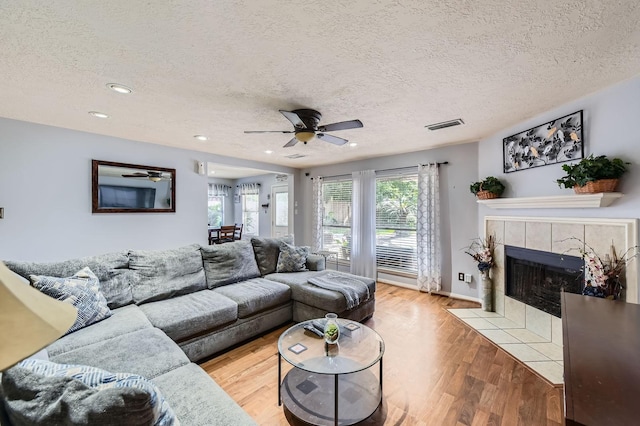 16307 Mango Ridge Ct, Humble, TX 77396 - living area featuring a textured ceiling, a ceiling fan, light wood-style floors, a tile fireplace, and recessed lighting