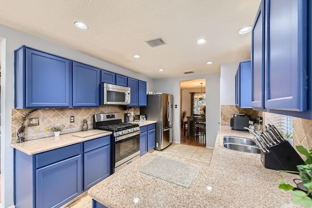 16307 Mango Ridge Ct, Humble, TX 77396 - kitchen with stainless steel appliances, blue cabinets, decorative backsplash, recessed lighting, and a chandelier