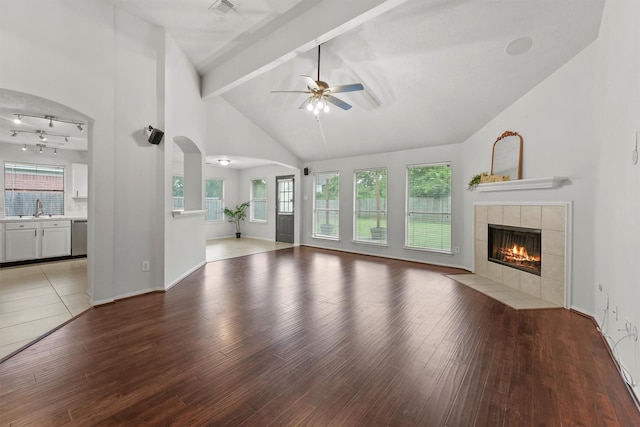 21327 Hadrian Dr, Katy, TX 77449 - unfurnished living room with a ceiling fan, a tile fireplace, beamed ceiling, wood finished floors, and healthy amount of natural light
