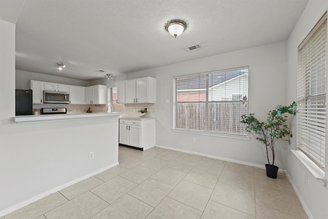 21327 Hadrian Dr, Katy, TX 77449 - kitchen featuring freestanding refrigerator, white cabinets, stainless steel microwave, light countertops, and a textured ceiling
