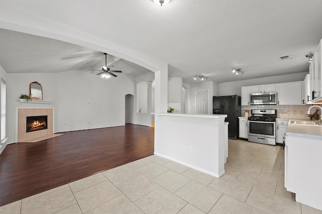 21327 Hadrian Dr, Katy, TX 77449 - kitchen featuring light tile patterned floors, appliances with stainless steel finishes, a ceiling fan, open floor plan, and arched walkways