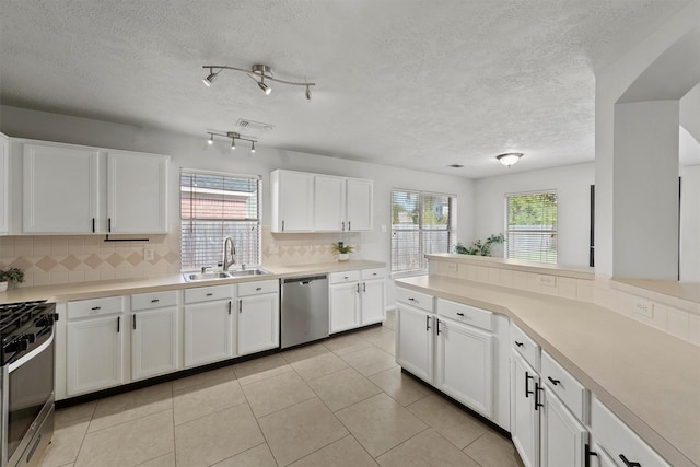 21327 Hadrian Dr, Katy, TX 77449 - kitchen with tasteful backsplash, healthy amount of natural light, stainless steel appliances, white cabinetry, and a textured ceiling