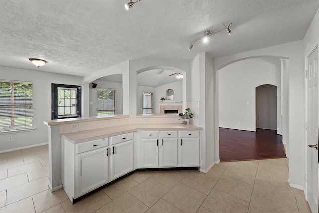 21327 Hadrian Dr, Katy, TX 77449 - kitchen with arched walkways, light tile patterned flooring, light countertops, white cabinets, and a textured ceiling