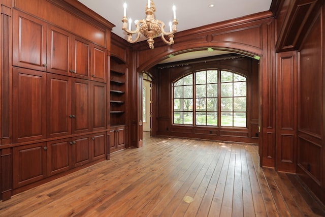 764 Kuhlman Rd, Hunters Creek Village, TX 77024 - unfurnished living room featuring a chandelier, arched walkways, built in shelves, hardwood / wood-style floors, and recessed lighting