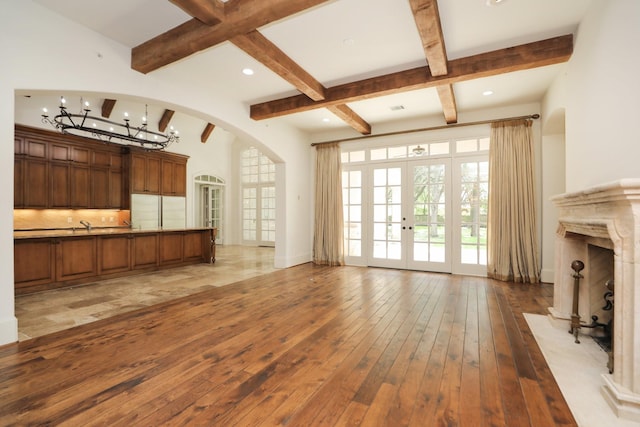 764 Kuhlman Rd, Hunters Creek Village, TX 77024 - unfurnished living room with arched walkways, beam ceiling, light wood-type flooring, a chandelier, and french doors