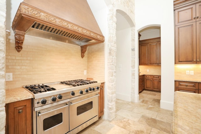 764 Kuhlman Rd, Hunters Creek Village, TX 77024 - kitchen featuring premium range hood, double oven range, backsplash, arched walkways, and light stone counters