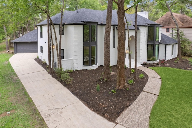 52 Indian Clover, The Woodlands, TX 77381 - view of front of house featuring brick siding, roof with shingles, a chimney, a front lawn, and concrete driveway