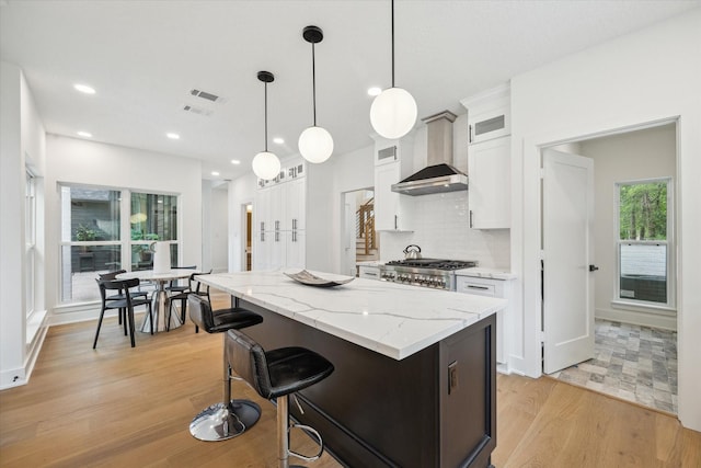 52 Indian Clover, The Woodlands, TX 77381 - kitchen with a center island, white cabinetry, light wood-type flooring, glass insert cabinets, and backsplash