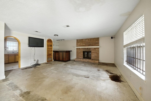 3819 Galway Ln, Houston, TX 77080 - unfurnished living room with concrete floors, a fireplace, and a textured ceiling