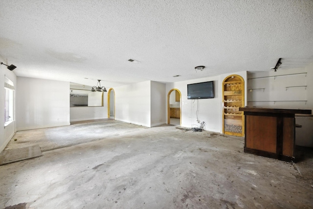 3819 Galway Ln, Houston, TX 77080 - unfurnished living room featuring unfinished concrete flooring, a textured ceiling, and arched walkways