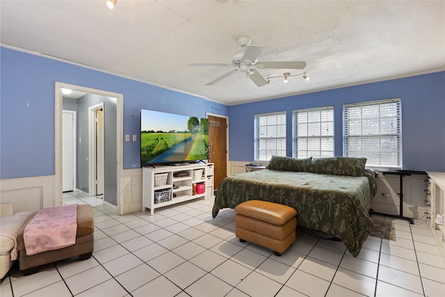 727 Baltic Ln, Houston, TX 77090 - bedroom with wainscoting, multiple windows, light tile patterned floors, a ceiling fan, and a textured ceiling