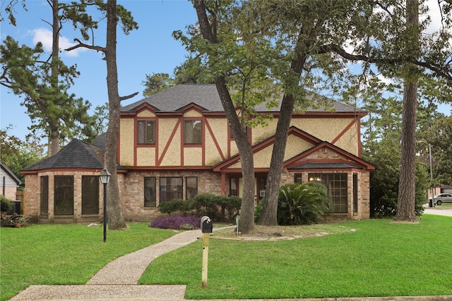 727 Baltic Ln, Houston, TX 77090 - tudor home featuring a shingled roof, a front yard, brick siding, and stucco siding