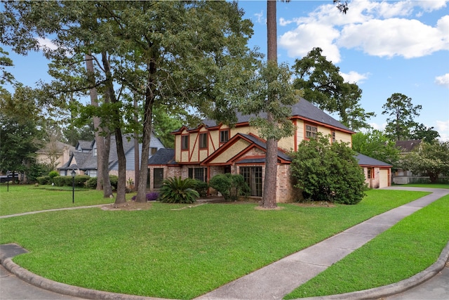 727 Baltic Ln, Houston, TX 77090 - tudor home with a front yard, a shingled roof, and brick siding