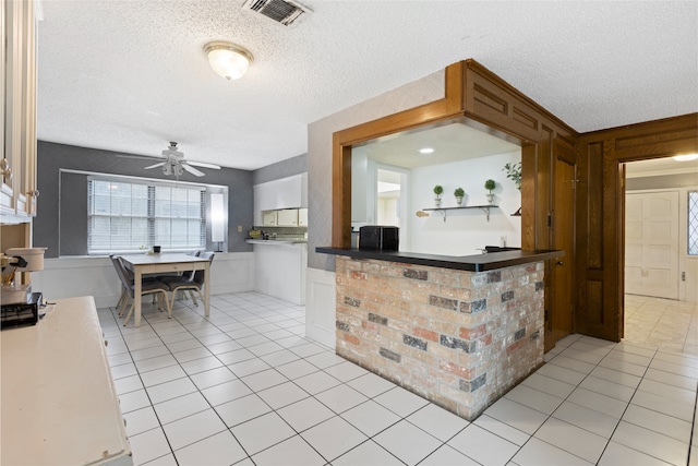 727 Baltic Ln, Houston, TX 77090 - kitchen featuring a textured ceiling, a ceiling fan, light tile patterned floors, and a wainscoted wall