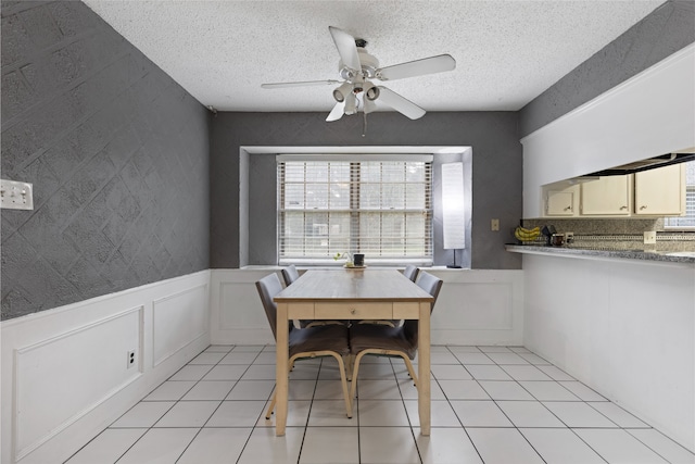 727 Baltic Ln, Houston, TX 77090 - dining area with a ceiling fan, a textured ceiling, wainscoting, a decorative wall, and light tile patterned floors