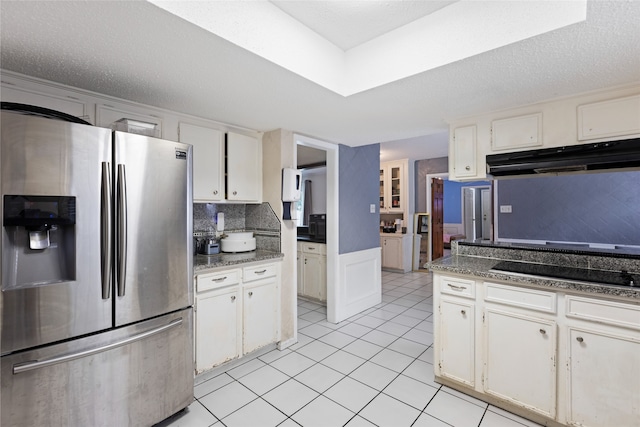 727 Baltic Ln, Houston, TX 77090 - kitchen with stainless steel fridge, white cabinets, light tile patterned floors, and under cabinet range hood