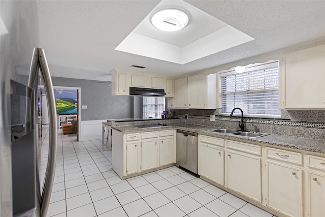 727 Baltic Ln, Houston, TX 77090 - kitchen with stainless steel appliances, a peninsula, light tile patterned floors, a wainscoted wall, and under cabinet range hood