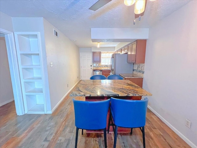 6305 Westward St Unit 106, Houston, TX 77081 - dining room featuring a textured ceiling, light wood-style flooring, ceiling fan, and built in shelves