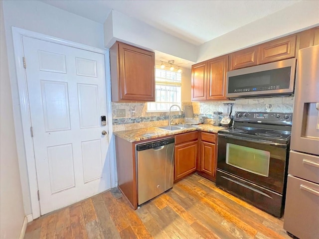 6305 Westward St Unit 106, Houston, TX 77081 - kitchen with stainless steel appliances, decorative backsplash, light wood-type flooring, brown cabinetry, and light stone countertops