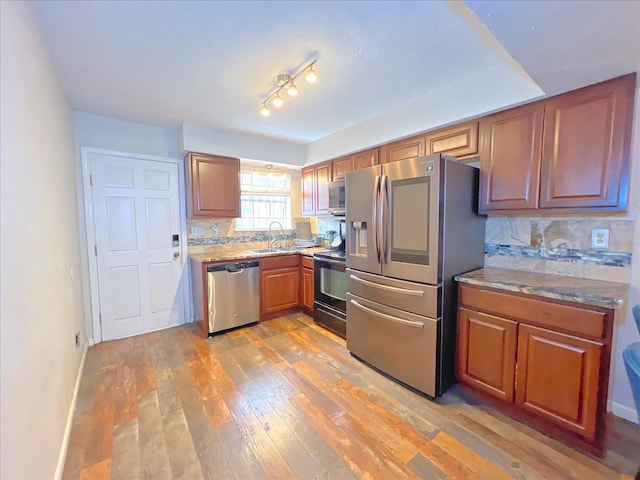 6305 Westward St Unit 106, Houston, TX 77081 - kitchen featuring appliances with stainless steel finishes, light wood-style flooring, backsplash, and brown cabinetry