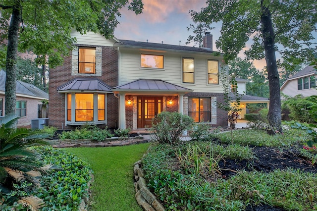 10 Featherfall Pl, Spring, TX 77381 - back of house at dusk with a chimney, brick siding, a yard, and a metal roof