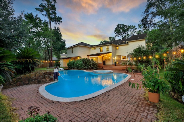10 Featherfall Pl, Spring, TX 77381 - pool at dusk with a fenced backyard, a pool with connected hot tub, a patio, and a wooden deck
