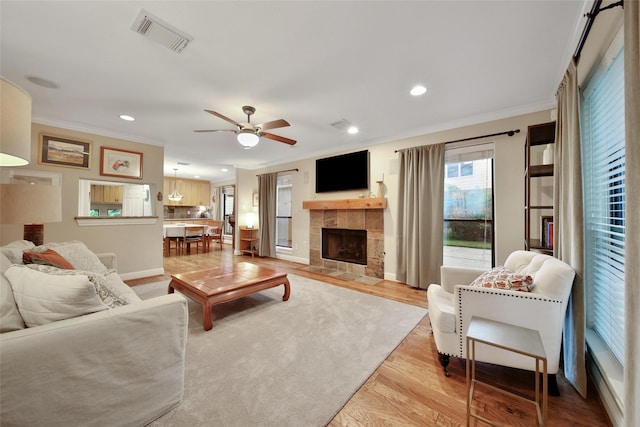 10 Featherfall Pl, Spring, TX 77381 - living room featuring ornamental molding, a ceiling fan, recessed lighting, a tiled fireplace, and light wood-style flooring