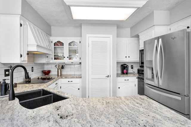 5934 Foresthaven Dr, Houston, TX 77066 - kitchen with stainless steel fridge with ice dispenser, white cabinetry, decorative backsplash, and light stone counters