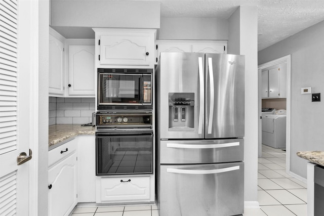 5934 Foresthaven Dr, Houston, TX 77066 - kitchen with black appliances, washer and clothes dryer, light tile patterned flooring, white cabinetry, and light stone counters