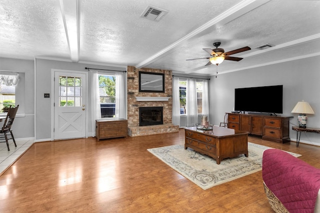 5934 Foresthaven Dr, Houston, TX 77066 - living area with a textured ceiling, light wood-type flooring, ceiling fan, a large fireplace, and beam ceiling
