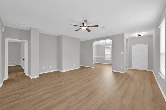 23911 Pinecreek Pt, Spring, TX 77373 - unfurnished living room with a ceiling fan, light wood-style floors, and arched walkways