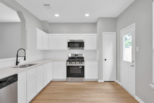 23911 Pinecreek Pt, Spring, TX 77373 - kitchen featuring stainless steel appliances, light wood finished floors, white cabinets, light countertops, and arched walkways