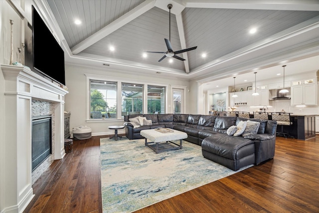 3848 S Main St, Anahuac, TX 77514 - living area featuring dark wood finished floors, a tiled fireplace, a ceiling fan, crown molding, and beamed ceiling
