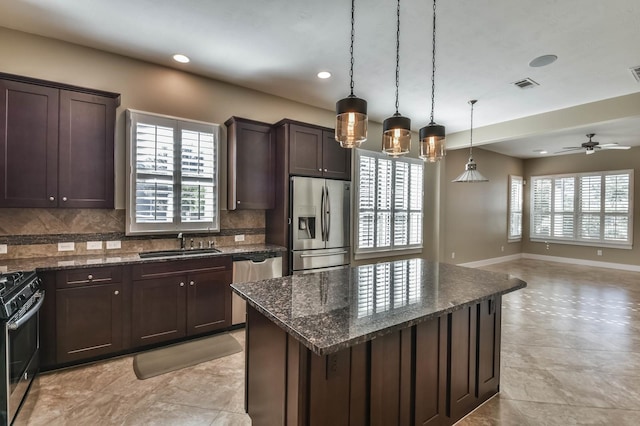 16803 Amelia Island Dr, Cypress, TX 77433 - kitchen featuring appliances with stainless steel finishes, dark brown cabinets, tasteful backsplash, open floor plan, and dark stone countertops