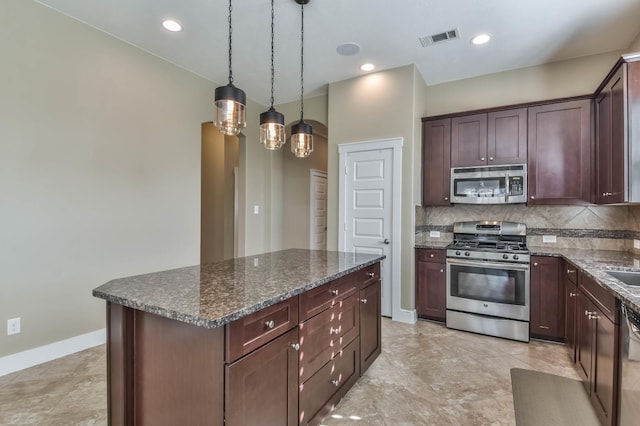 16803 Amelia Island Dr, Cypress, TX 77433 - kitchen with stainless steel appliances, backsplash, a kitchen island, dark stone countertops, and hanging light fixtures