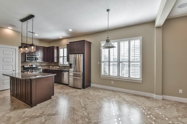 16803 Amelia Island Dr, Cypress, TX 77433 - kitchen featuring stainless steel appliances, dark brown cabinetry, backsplash, dark stone counters, and hanging light fixtures