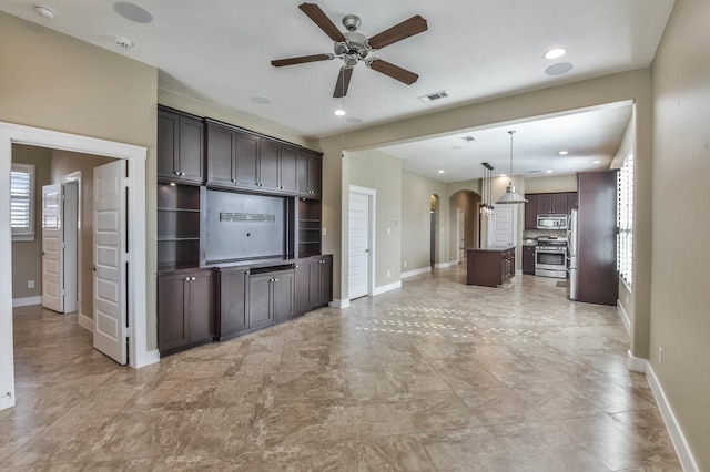 16803 Amelia Island Dr, Cypress, TX 77433 - kitchen featuring ceiling fan, arched walkways, stainless steel appliances, dark brown cabinets, and a center island