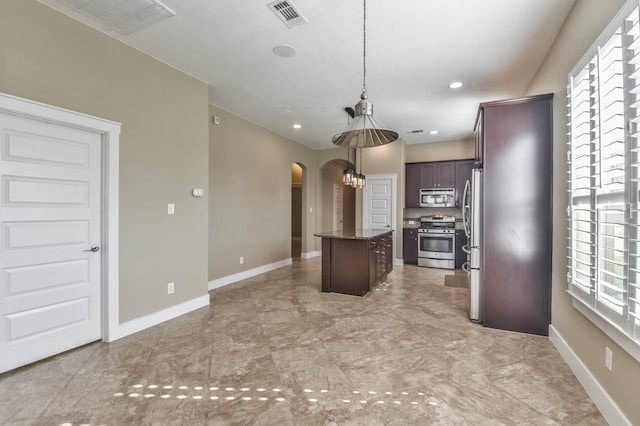 16803 Amelia Island Dr, Cypress, TX 77433 - kitchen with arched walkways, a kitchen island, stainless steel appliances, backsplash, and hanging light fixtures