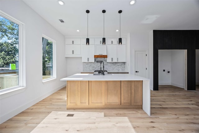 2206 Bleker St, Houston, TX 77026 - kitchen featuring decorative backsplash, light countertops, light wood-type flooring, recessed lighting, and white cabinets