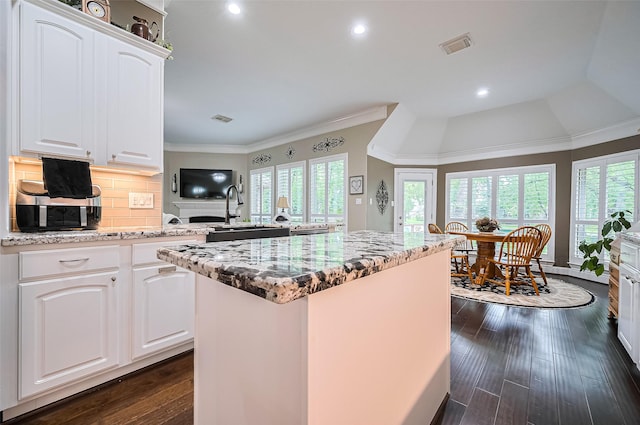 9427 Fern Wood Frst, Houston, TX 77040 - kitchen with light stone counters, tasteful backsplash, a kitchen island, dark wood finished floors, and white cabinetry