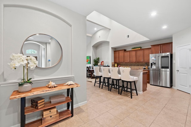 9707 Old Timber Ln, Spring, TX 77379 - kitchen with stainless steel fridge with ice dispenser, brown cabinetry, a kitchen breakfast bar, tasteful backsplash, and recessed lighting