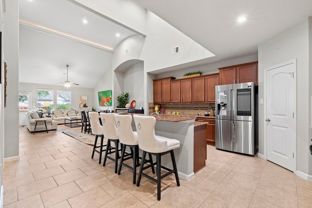 9707 Old Timber Ln, Spring, TX 77379 - kitchen featuring stainless steel fridge, brown cabinetry, a breakfast bar, a ceiling fan, and high vaulted ceiling