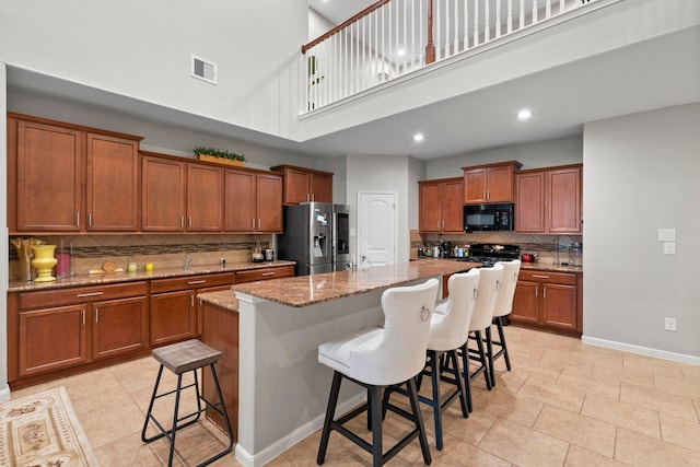 9707 Old Timber Ln, Spring, TX 77379 - kitchen featuring backsplash, brown cabinets, a high ceiling, a kitchen bar, and stainless steel refrigerator with ice dispenser