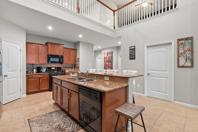 9707 Old Timber Ln, Spring, TX 77379 - kitchen with black appliances, brown cabinets, a towering ceiling, light stone counters, and a kitchen breakfast bar