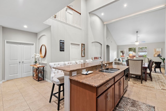 9707 Old Timber Ln, Spring, TX 77379 - kitchen featuring a kitchen bar, a high ceiling, light stone countertops, light tile patterned flooring, and an island with sink