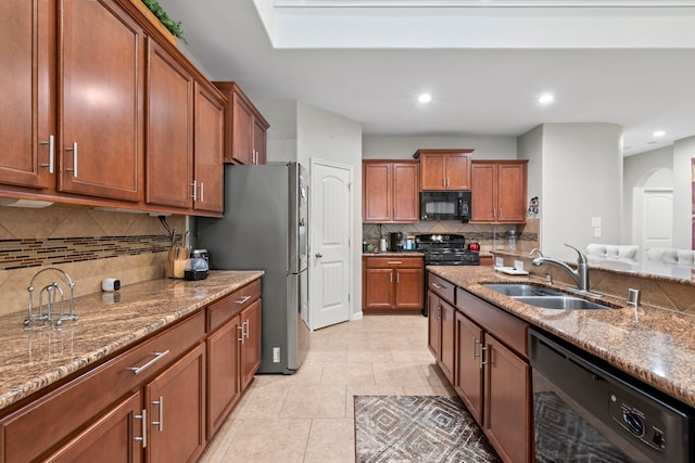 9707 Old Timber Ln, Spring, TX 77379 - kitchen with black appliances, light stone counters, decorative backsplash, brown cabinetry, and recessed lighting