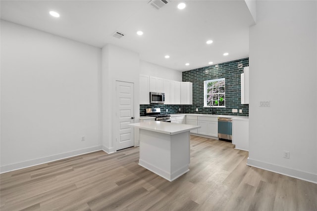2012 Chew St, Houston, TX 77020 - kitchen featuring backsplash, a kitchen island, white cabinets, light wood-style floors, and recessed lighting