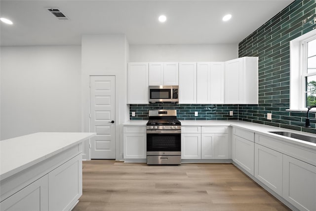 2012 Chew St, Houston, TX 77020 - kitchen featuring appliances with stainless steel finishes, recessed lighting, decorative backsplash, light countertops, and white cabinetry